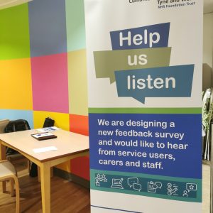 A banner that advertises the Points of You Survey. The banner is in the foyers within CNTW hospitals with a table and chair in the background